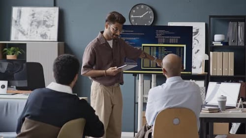 Indischer Softwareingenieur präsentiert Code einem multiethnischen IT-Team im Büro