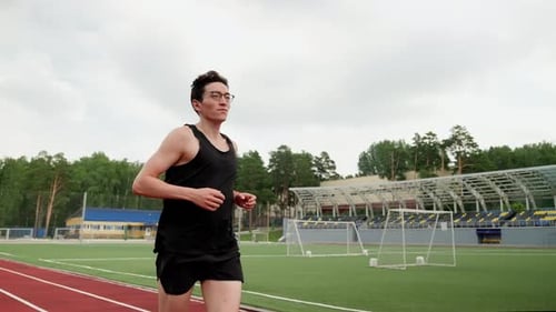 Asianlooking Man Running on the Background of a Football Field