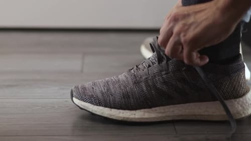 Left view of running shoes of a man tying his shoelaces before going out for a run