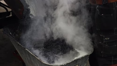 Steaming Asphalt Being Poured into Wheelbarrow