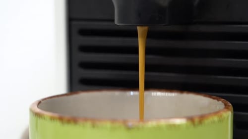 Fresh Hot Coffee Elegantly Pouring Into Green Mug From Espresso Machine Close Up In Slow Motion