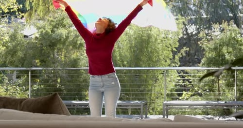 Woman Twirls with Pride Flag on Balcony
