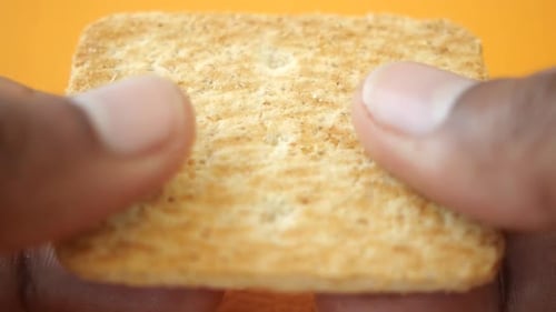 Crunchy Snack Being Held Against a Vibrant Orange Background