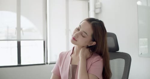 A young professional enjoys a moment of stretching to relieve tension in a modern office setting.