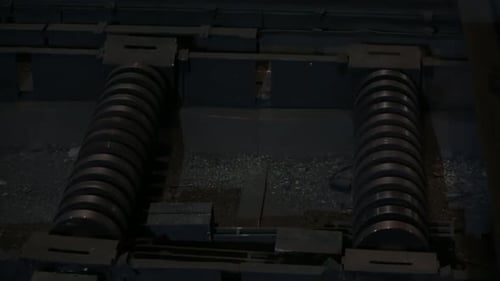 Glowing Metal Bars Moving Across Factory Rollers
