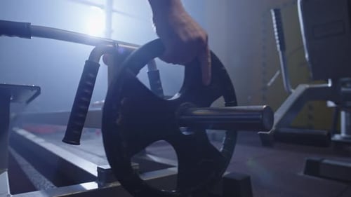 Closeup of Athlete's Hands Putting Weight on Barbell in Gym