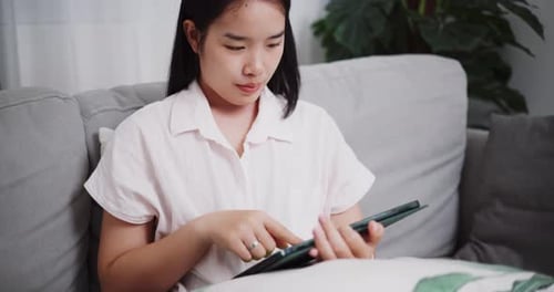 Woman Using Tablet Device on Sofa at Home