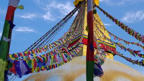 Lines of prayer flags blowing in the wind with the golden Boudhanath stupa temple in Kathmandu Nepal