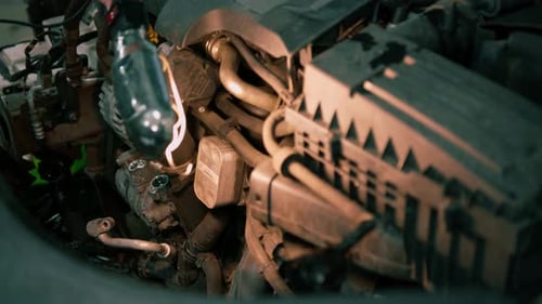 A male auto mechanic with a flashlight in his hands inspects the car engine and looks for faults