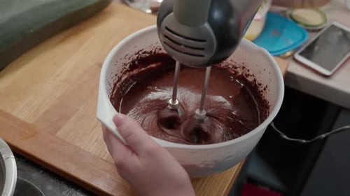 Mixing Dark Batter with Electric Mixer in White Bowl