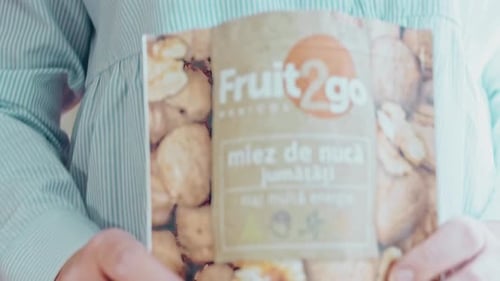 Woman Pours Walnuts on a Wooden Board