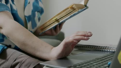 Working with a Laptop and a Book at Home