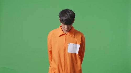 Asian Male Prisoner In Handcuffs Walking On The Green Screen Background
