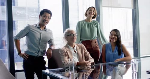 Smiling business team posing together around conference table in modern office