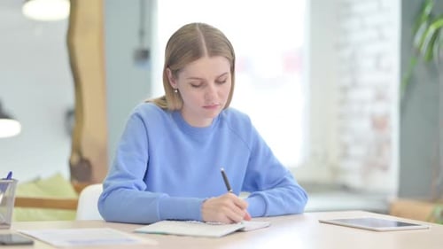 Woman Writing in Notebook at Desk