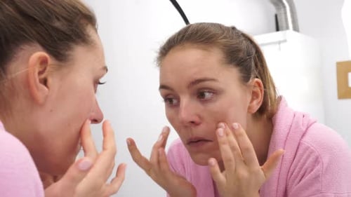 Woman Cleaning Face With Scrub In Bathroom
