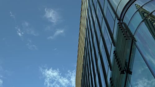 Curved glass facade of a modern skyscraper against a clear blue sky.