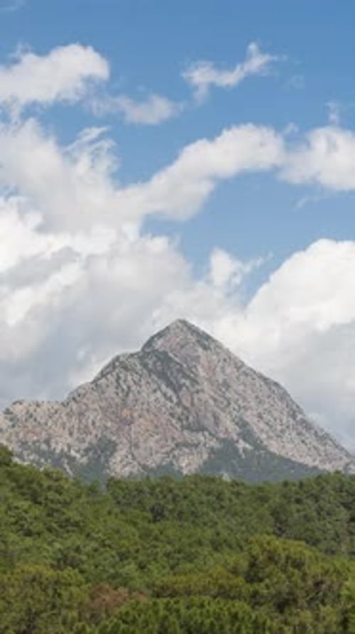 Vertical video. Timelapse Clouds Swiftly Flying Above Mountains, Revealing Blue Sky.
