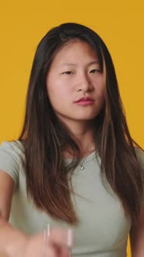 Young woman making denial gesture looking at camera, isolated over yellow background in studio