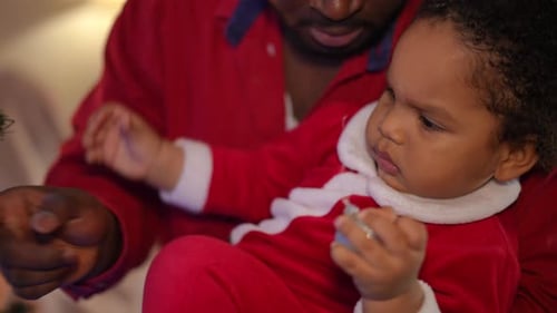 Dad and Child Decorate Christmas Tree with Ornaments