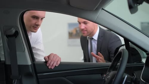 A Young Man is Talking to a Car Salesman A Guycustomer Buys a Vehicle in the Showroom
