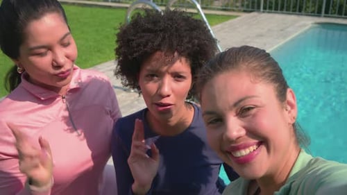 Amigas diversas estendendo o braço na piscina gravando selfie usando o telefone, capturando laços de amizade
