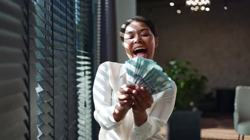 Multiracial Woman with Beaming Smile Holding Fan of Dollar Banknotes at Office