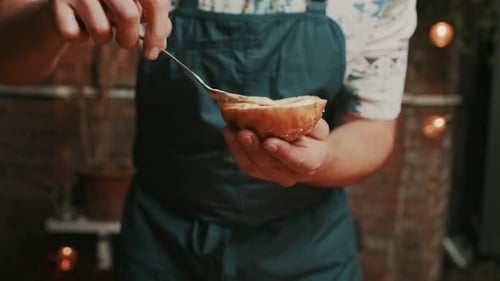 Chef adds homemade mayonnaise onto burger bun and places it on hot smoky outdoor grill. Medium close