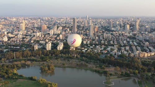 Aerial Shot Of Hot Air Balloon Descending Over Yarkon Park Against Sky In City