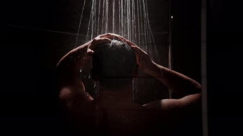 Adult Male Showering and Washing Hair in Dark Setting