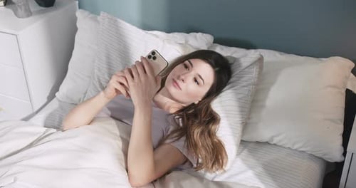 Woman Using Smartphone While Lying in Bed