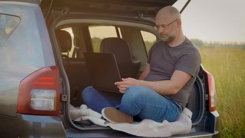 Homem adulto, estudante universitário, aprendendo on-line usando um laptop, fazendo anotações, assistindo webinars ou