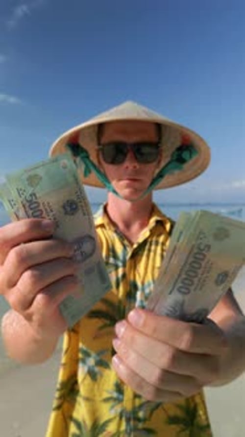 Man Counting Vietnamese Dong on the Tropical Beach in Vietnam
