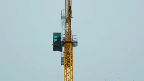 Turmdrehkran im Einsatz auf der Baustelle vor bewölktem Himmel Schwerlastgerät rotierend und