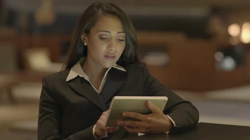 A Young Businesswoman is Focused on Her Work While Using a Tablet in a Modern Office Setting