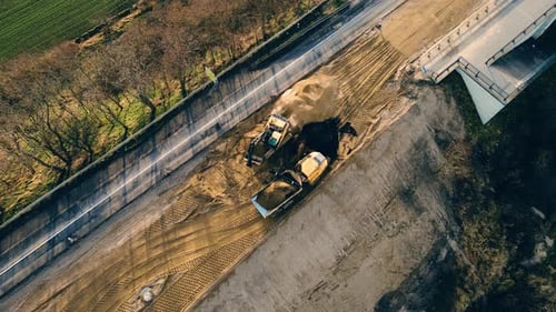 Excavator Loads Dump Truck on Construction Site