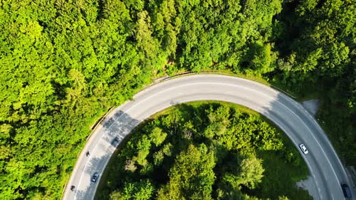 Schleife der Straße, die das üppige Grün überquert. Autos, die im Wald auf der Autobahn fahren. Ansicht von oben.