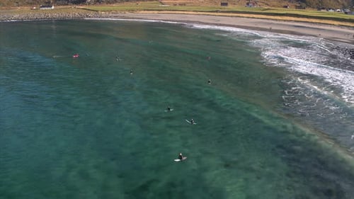 Drone aerial of multiple surfers floating paddling on surf boards in the ocean beach scene