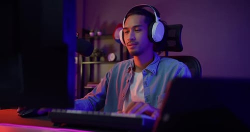 Chico asiático feliz, jugador, usa auriculares, participación, juega a videojuegos, coloridas luces de neón