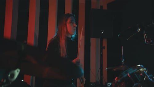 Woman Playing Drums Energetically at Night in Studio