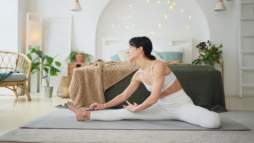 Woman Stretching Leg Muscles on Yoga Mat Indoors