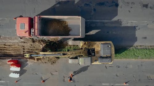 Large Crawler Excavator Digging Ground and Load It Into Dump Truck on Road
