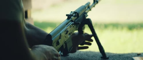 Man Preparing Rifle for Shooting with Outdoor View in Bright Natural Setting