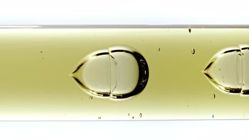Gel cosmétique transparent avec bulles moléculaires et huile s'écoulant dans un tube en verre avec liquide transparent