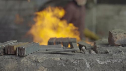 A Ironworker Fuelling A Fire In A Iron Forging Workshop