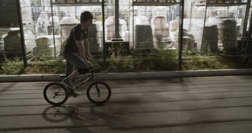 Male Cyclist Riding BMX in Evening Town Near Building