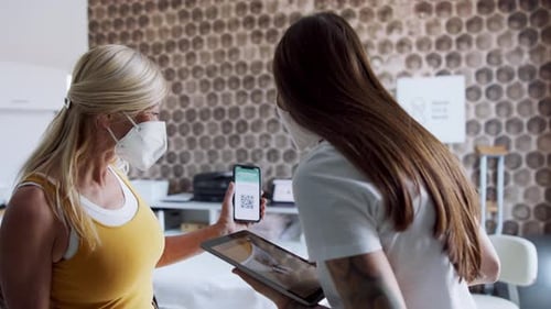 Woman Showing Covid Pass to Nurse in Clinic