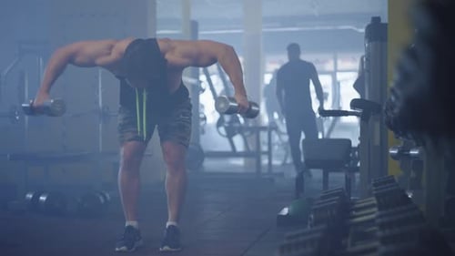 Athletic Caucasian Man Doing Fitness and Working Out in the Middle of the Gym