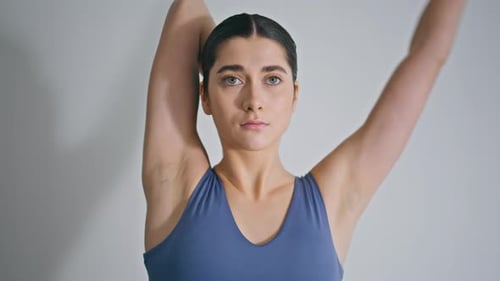 Young Woman Stretching Arms Indoors in Gym Clothing