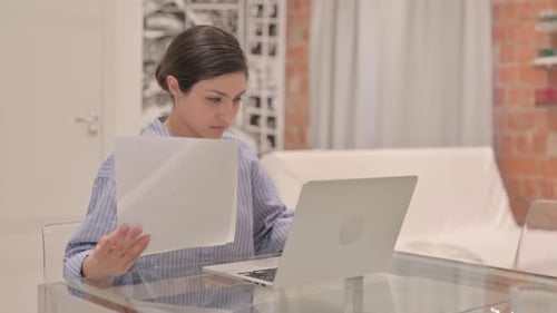 Woman Working with Laptop and Paper at Home